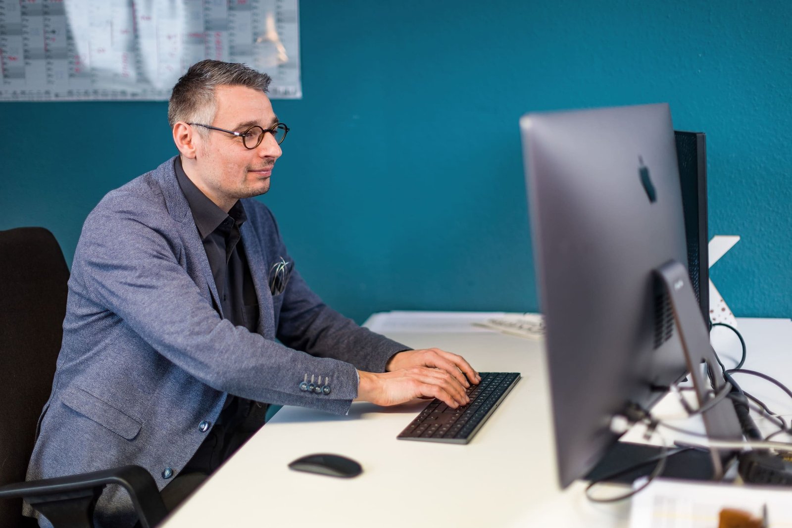 Patrick Schnelle sitzt an seinem Schreibtisch und arbeitet am Computer